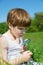 Adorable Little Boy Watching Daisy Carefully Through The Magnifying Glass On Green Meadow On Sunny Spring Day