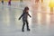 Adorable little boy in winter clothes with protections skating o