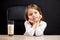 Adorable little child female sitting at table with a glass of milk