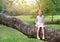 Adorable little child girl climb and resting on big tree trunk in the garden outdoor