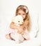 Adorable little child girl sit in the bed with her toy. The child girl hugs the teddy bear.