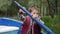 Adorable little child in life jacket sitting in boat and holding wooden paddle. Charming boy tries to steer and rows boat. Cute li