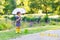 Adorable little child in yellow rain boots and umbrella in summer park
