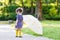 Adorable little child in yellow rain boots and umbrella in summer park