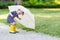 Adorable little child in yellow rain boots and umbrella in summer park