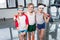 Adorable little children in sportswear standing embracing and smiling at camera in gym