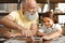 Adorable little girl assembling jigsaw puzzle with her grandfather