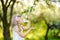 Adorable little girl in blooming apple tree garden on beautiful spring day.