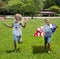 Adorable little girl and boy run on bright green grass holding american flag outdoors on beautiful summer day