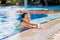 Adorable little girl in bright swimsuit in swimming pool on vacation on sunny summer day. Family vacation concept