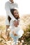 Adorable little girl with curly hair laughing in the arms of her older brother