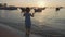 Adorable little girl in a dress jumping in water with splashes on the beach.