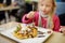 Adorable little girl eating bubble waffle with fruits, chocolate and marshmallows. Children eating sweets.