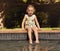 Adorable little girl enjoying sitting by edge of pool