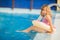 Adorable little girl with inflatable life vest having fun in the pool