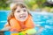 Adorable little girl with inflatable life vest having fun in the pool