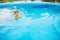 Adorable little girl with inflatable life vest having fun in the pool