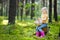 Adorable little girl picking foxberries in the forest