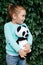 Adorable little girl playing knitted panda toy outdoor