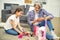 Adorable little girl playing with smiling grandfather showing him dollhouse