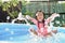 adorable little girl playing splash water in a blue rubber pool.