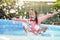 adorable little girl playing splash water in a blue rubber pool.