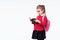 Adorable little girl in red school jacket, black dress, backpack and rounded glasses emotionally looking at book while