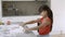 Adorable little girl rolling dough on kitchen table