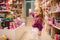 Adorable little girl shopping for toys. Cute female in toy store. Happy young girl selecting toy