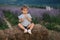 Adorable little girl sits on hay by the farm. Background of summer lavender field. Cute girl in striped t-shirt and blue