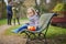 Adorable little girl sitting on the bench with lunchbox and having picnic on a spring day