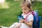 Adorable little girl sitting on the grass with backpack. Cute little girl drinking juise outdoors