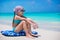 Adorable little girl sitting on surfboard at the