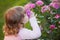 Adorable little girl smelling garden roses.