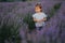 Adorable little girl walking in lavender field after sunset. Blue or purple lavender. Girl close her eyes like hide
