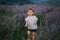 Adorable little girl walking in lavender field after sunset. Blue or purple lavender. Happy kid smile, run and jump.