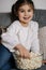 Adorable little girl watching TV at home and laughs. Cute girl eating popcorn. Holiday mood