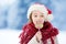 Adorable little girl wearing Santa hat having huge striped Christmas lollipop on beautiful winter day
