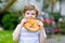 Adorable little kid boy eating huge big bavarian german pretzel.