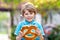 Adorable little kid boy eating huge big bavarian german pretzel.