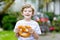 Adorable little kid boy eating huge big bavarian german pretzel.