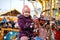 Adorable little kid girl riding on a carousel horse at Christmas funfair or market, outdoors.