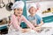 adorable little kids in chef hats and aprons smiling at camera while cooking together