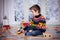 Adorable little preschool boy, playing with wooden trains and ra