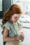 adorable little red haired girl drinking milkshake from glass