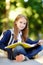 Adorable little schoolgirl studying outdoors on bright autumn day. Young student doing her homework. Education for small kids.