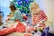 Adorable little sisters wearing Christmas pajamas opening gifts and unwrapping presents on Christmas morning.