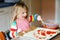 Adorable little toddler girl making italian pizza at home. Cute happy child having fun in home kitchen, indoors. Kid