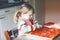 Adorable little toddler girl making italian pizza at home. Cute happy child having fun in home kitchen, indoors. Kid