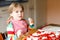 Adorable little toddler girl making italian pizza at home. Cute happy child having fun in home kitchen, indoors. Kid